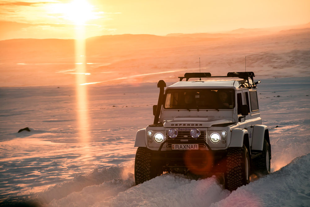 A Jeep Defender drives up the road at sunset. Photo by Mike Higdon